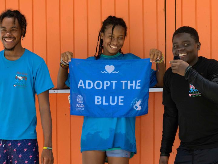 A group of kids holding a blue Adopt the Blue flag.